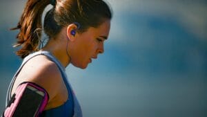 woman wearing smartphone armband and blue earphones